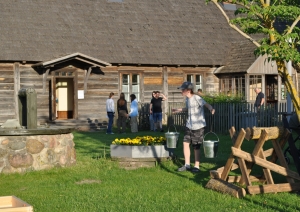 Muzeja apmeklētāji iemēģina darbā muzeja eksponātu ūdens nešanu nēšos