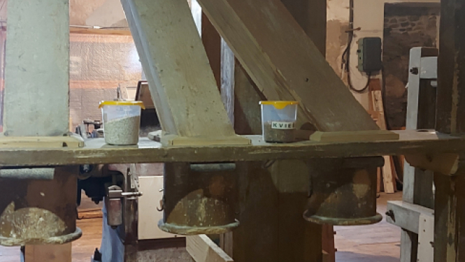 Graudu malšanas telpa dzirnavās, kura balstās uz koka un betona stabiem