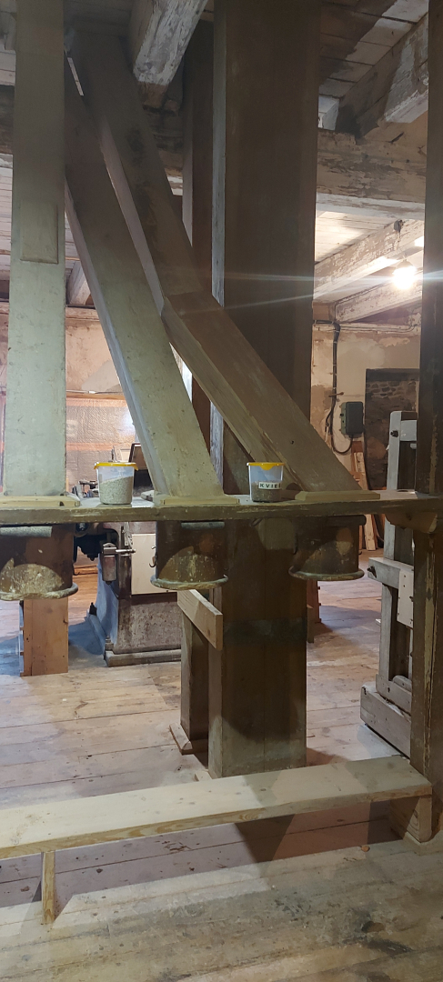 Graudu malšanas telpa dzirnavās, kura balstās uz koka un betona stabiem