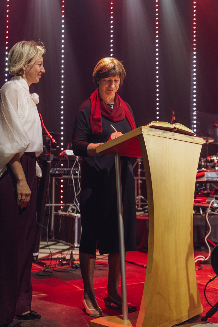 Sieviete parakstās Dobeles novada pašvaldības apbalvojumu goda grāmatā, cita sieviete asistē