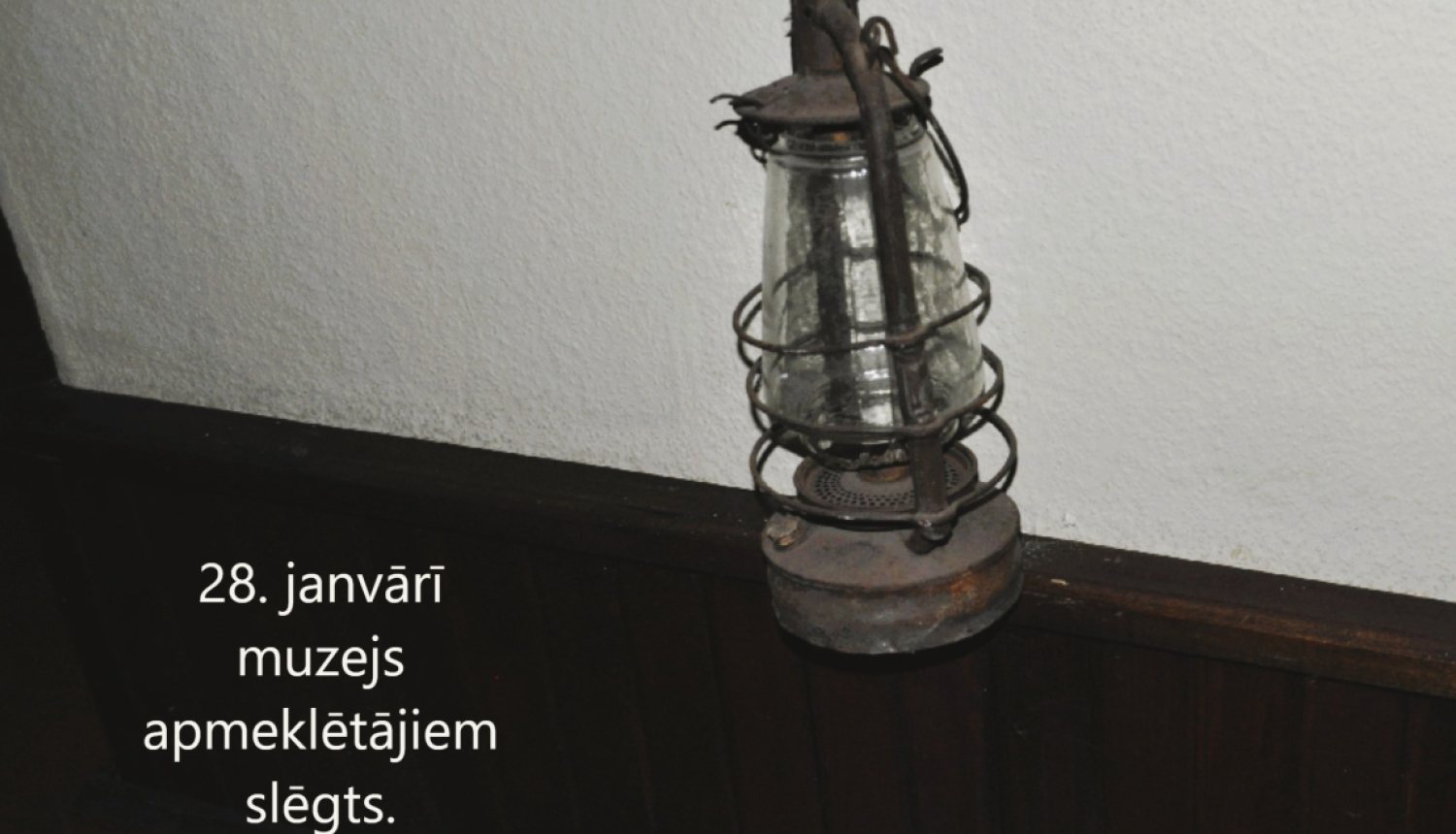Petrolejas lampa uzkarināta pie gaišas sienas