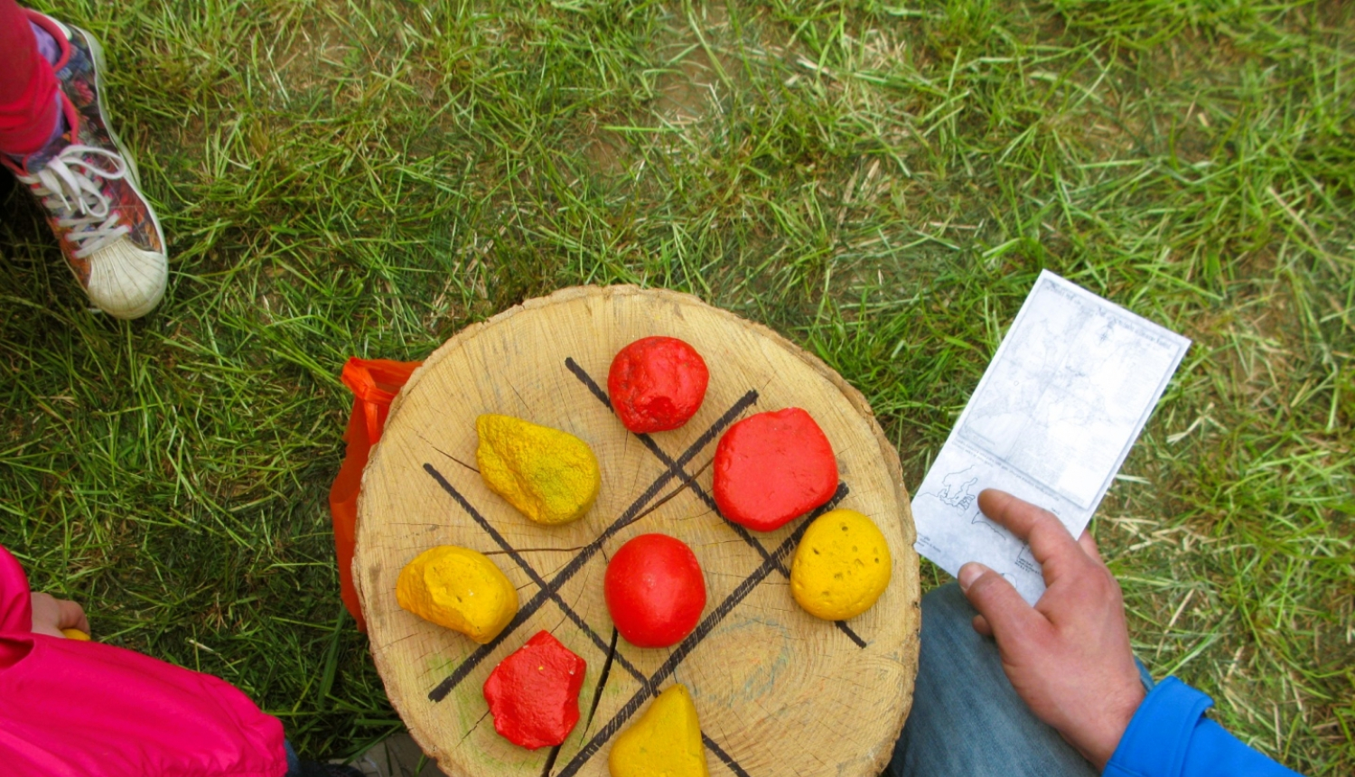 Spēle no krustiņiem un aplīšiem uz celma ar krāsainiem akmeņiem